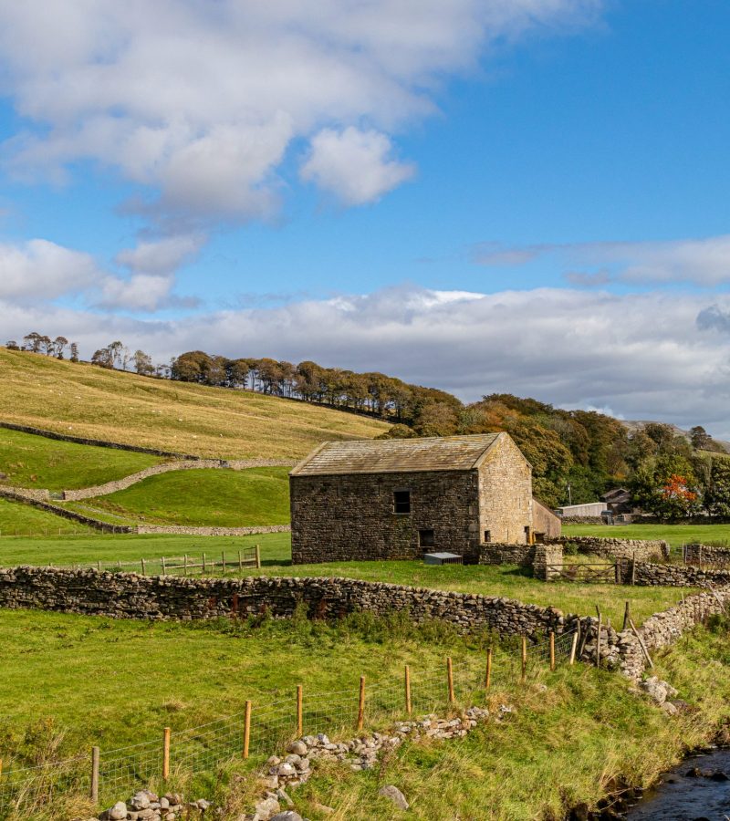 stone-barn-sits-field-with-stone-wall-small-stone-building-background